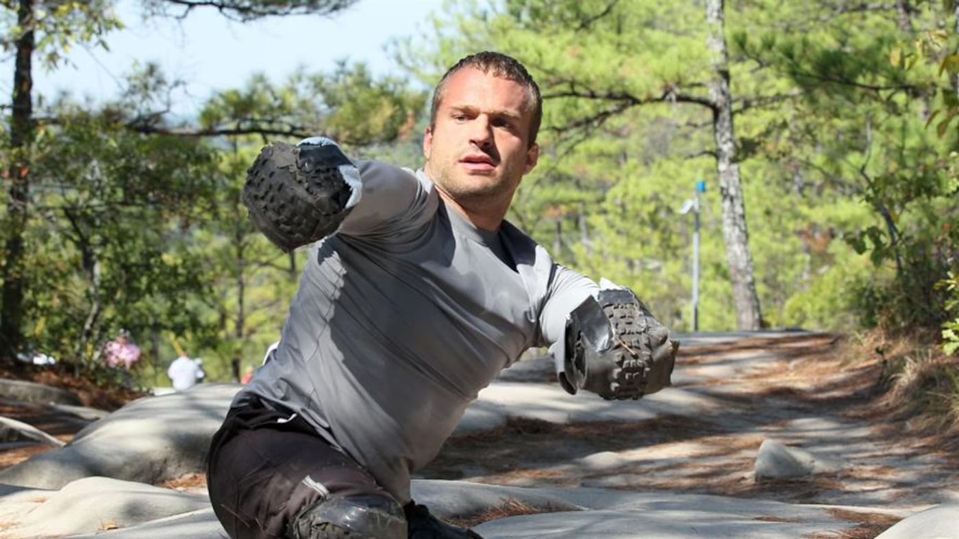 Kyle Maynard bear crawling a trail on custom tire-tread arm pads