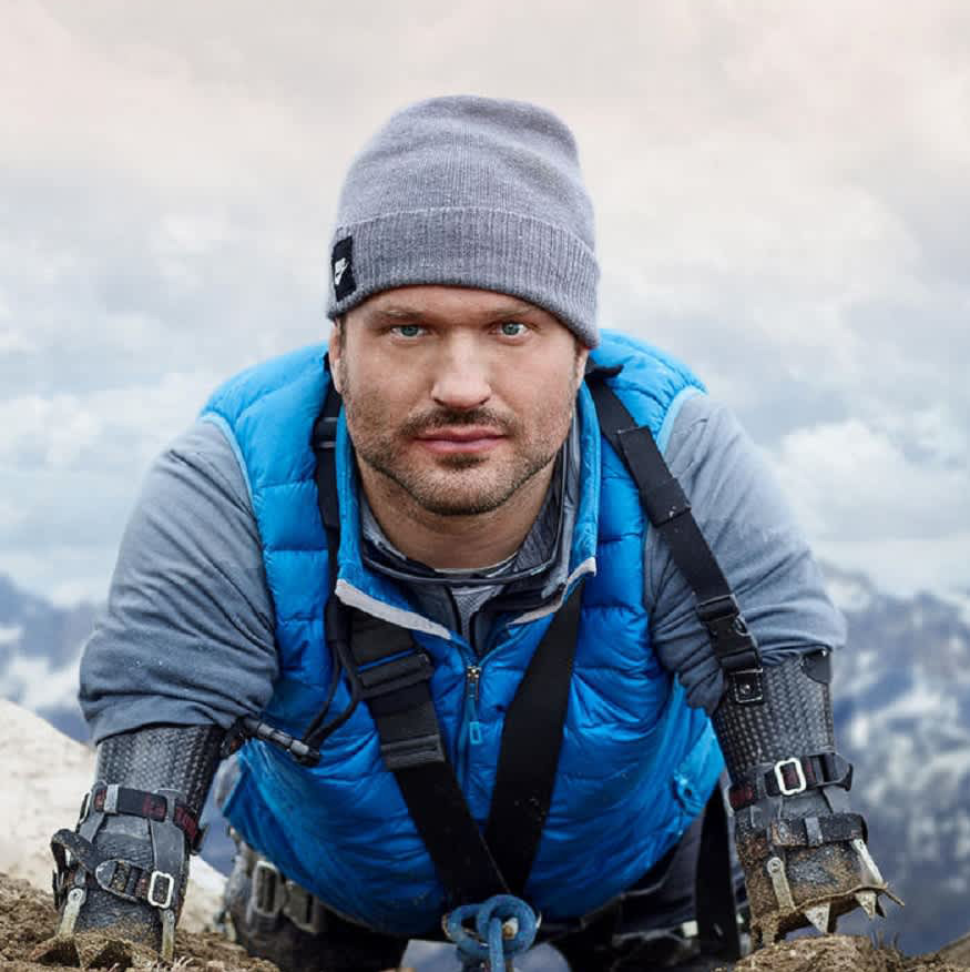 Kyle Maynard crawling toward the camera on a mountain in winter gear